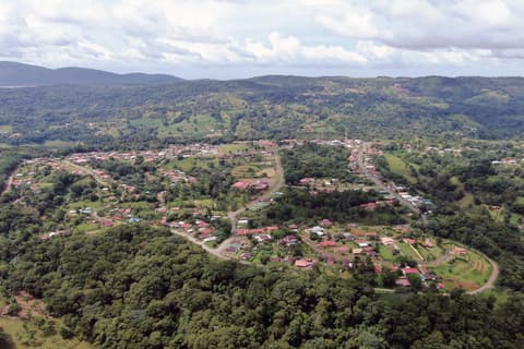 Vista aérea de Nuevo Arenal, con casas entre colinas verdes y bosque.