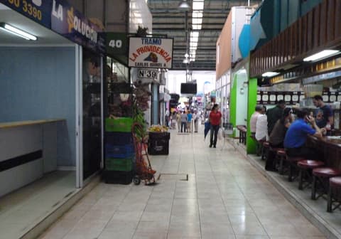 Pasillo interior del mercado municipal de Ciudad Quesada, con tramos a los lados y personas comiendo en una soda.