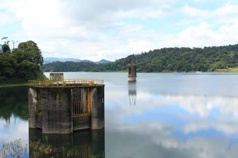Estructuras de concreto sobre el agua del lago Arenal, cerca de la represa, con bosque en la otra orilla.