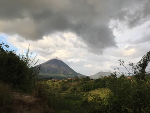 El volcán Arenal y el cerro Chato vistos desde la zona de El Castillo, bajo nubes de lluvia.